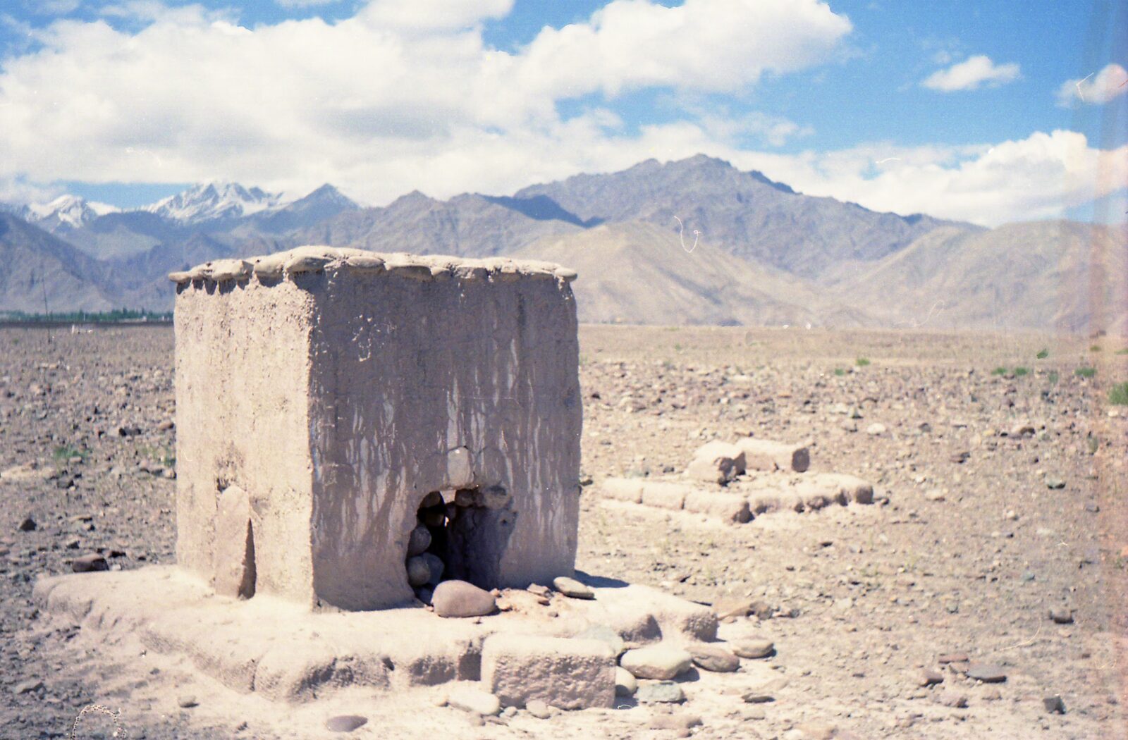 An earthen structure on a rocky plain beneath mountains in Tibet